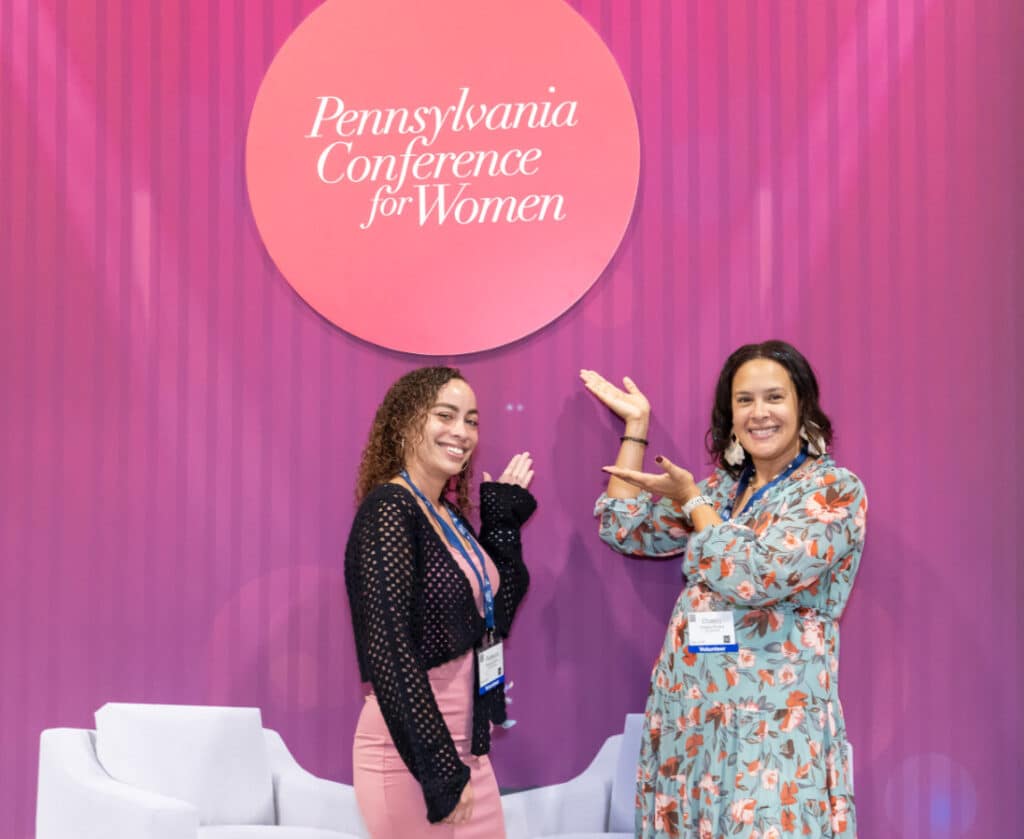 Pennsylvania Conference for Women 2024 attendees in front of PA CFW logo back drop